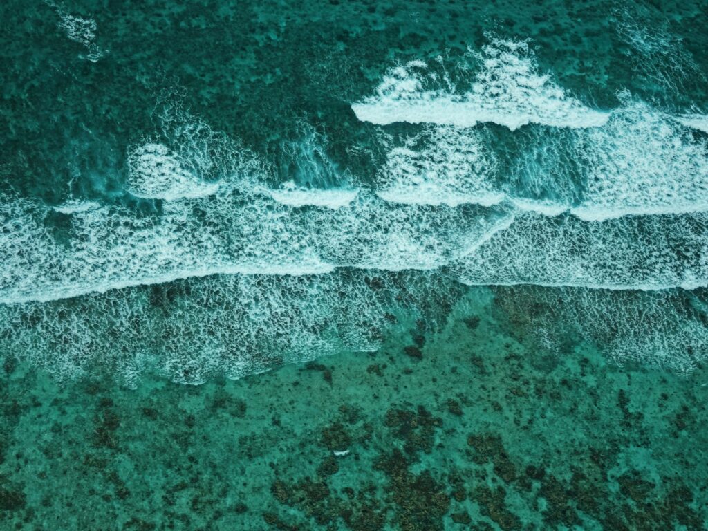 aerial view of a series of three waves breaking onto shore