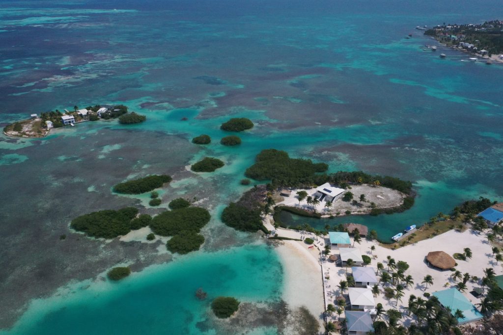 aerial photo of belize white sand beach and houses contrasting against blue waters
